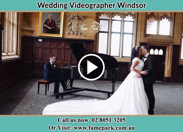 The newlyweds kissing with the pianist playing music Windsor NSW 2756